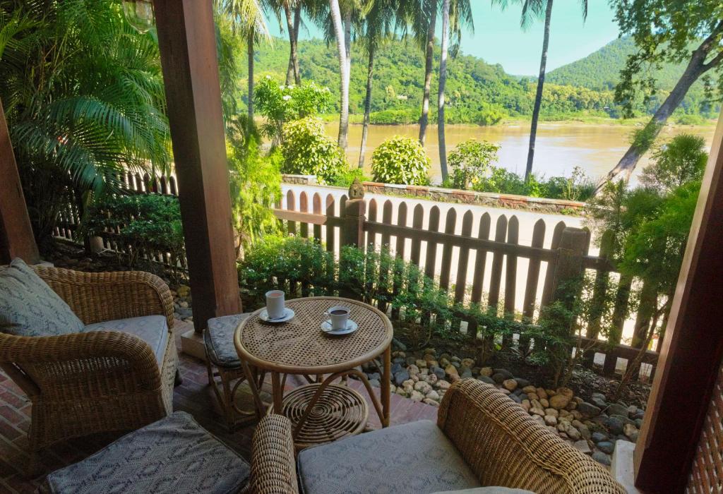 een veranda met een tafel en stoelen en uitzicht op een rivier bij Mekong Riverview Hotel in Luang Prabang