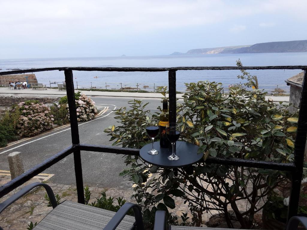 einen Tisch mit zwei Gläsern Wein auf dem Balkon in der Unterkunft Sennen Cove Retreat in Sennen Cove