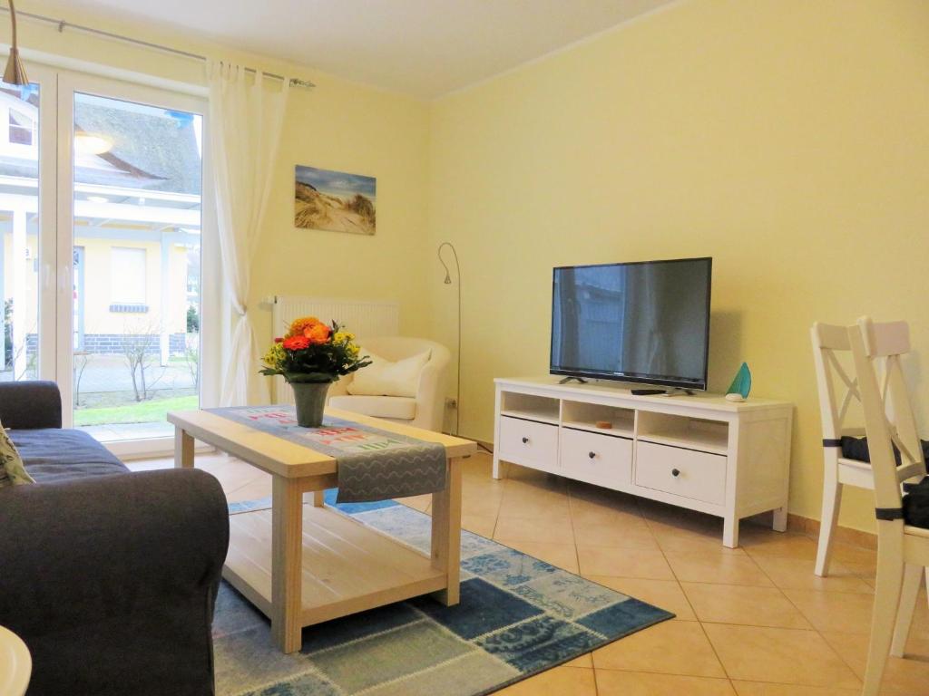 a living room with a television on a white cabinet at Lindenstraße 43, Whg 1 - Nord bei Nordost in Zingst