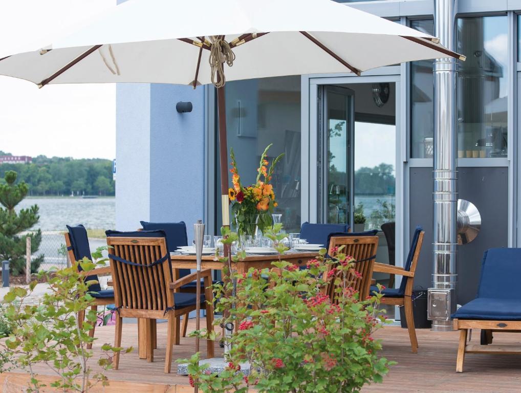 a table and chairs with an umbrella on a deck at Ostsee - Reetdachhaus Nr 5 "Beaufort" im Strand Resort in Heiligenhafen