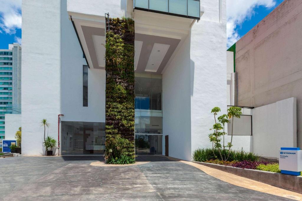 a large white building with a vertical garden at Wyndham Puebla Angelopolis in Puebla