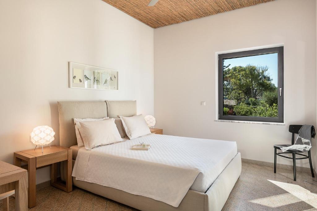 a white bedroom with a bed and a window at Myrtia Beach House in Tersanas