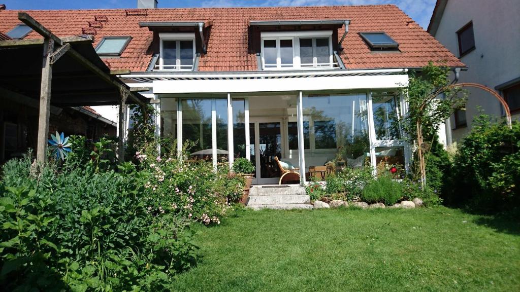 une maison avec des portes en verre et un chien assis dans la cour dans l'établissement Ferienhaus Feder, à Lichtenau