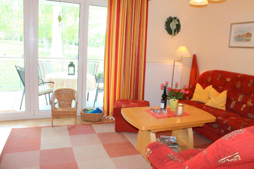 a living room with a red couch and a table at Residenz am Kurpark - Whg 12 - familienfreundliche Wohnung, strandnah und zentral gelegen, WLAN in Grömitz