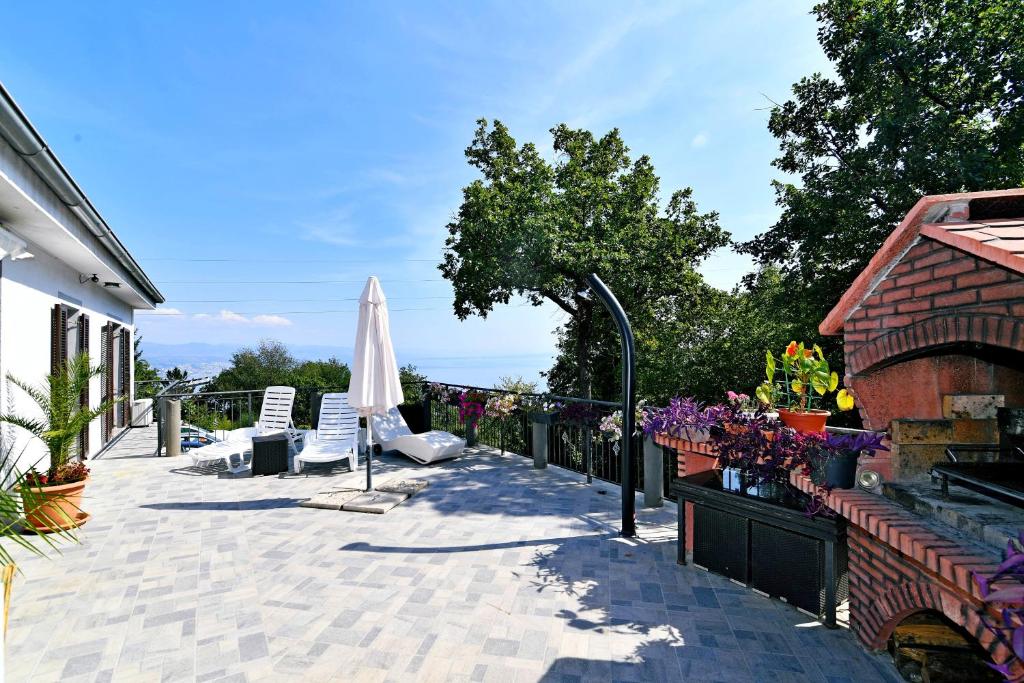 a patio with a umbrella and chairs and a fence at Apartman SÙŠANJ in Opatija