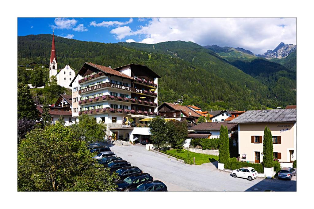 een groot gebouw met auto's geparkeerd op een parkeerplaats bij Alpenhotel in Oetz