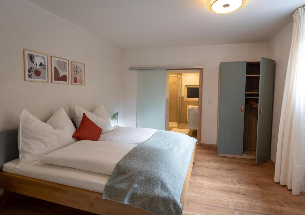 毛拉赫的住宿－Dorfapartment Achensee，一间卧室配有带白色床单和红色枕头的床。