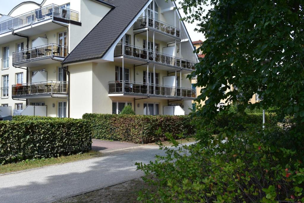 a white apartment building with balconies and a driveway at Am Kurpark " Nr 812" in Baabe