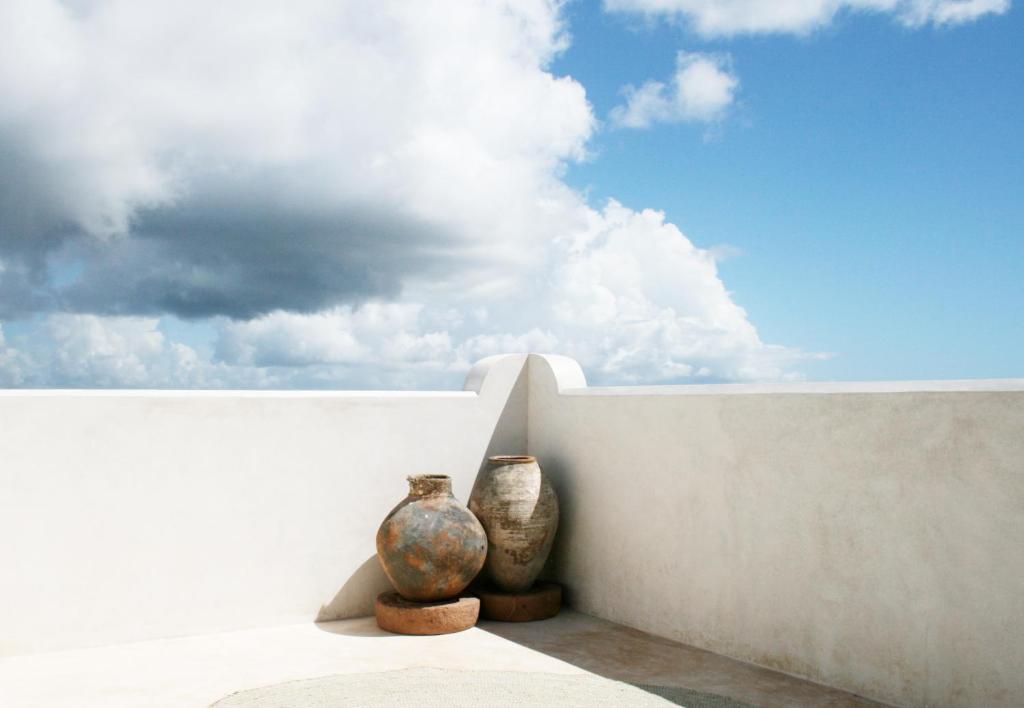 two vases are sitting next to a wall at Jua House in Lamu