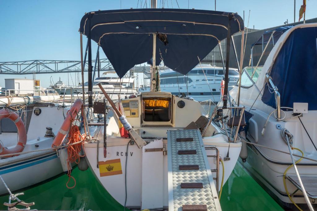 un barco atracado en un puerto deportivo con una escalera en él en Pequeño velero en Port Forum ideal para Backpackers en Barcelona