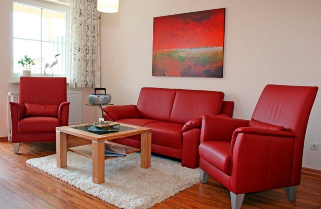 a living room with two red chairs and a coffee table at "Landhaus Voss" Typ 2 Nr8 in Staberdorf