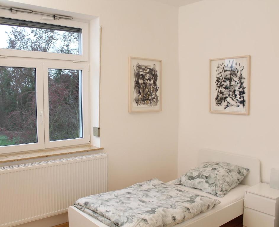 Cette chambre blanche dispose d'un lit et d'une fenêtre. dans l'établissement Haus Roy Ferienwohnung 1Etage, à Zülpich