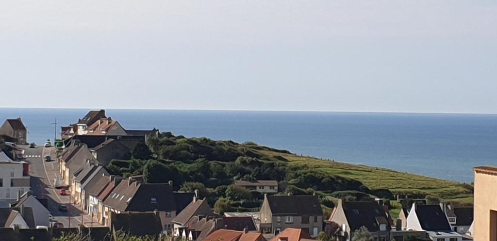 a town with houses and the ocean in the background at Entre ciel et mer, Maison neuve vue mer proche de la plage in Équihen-Plage