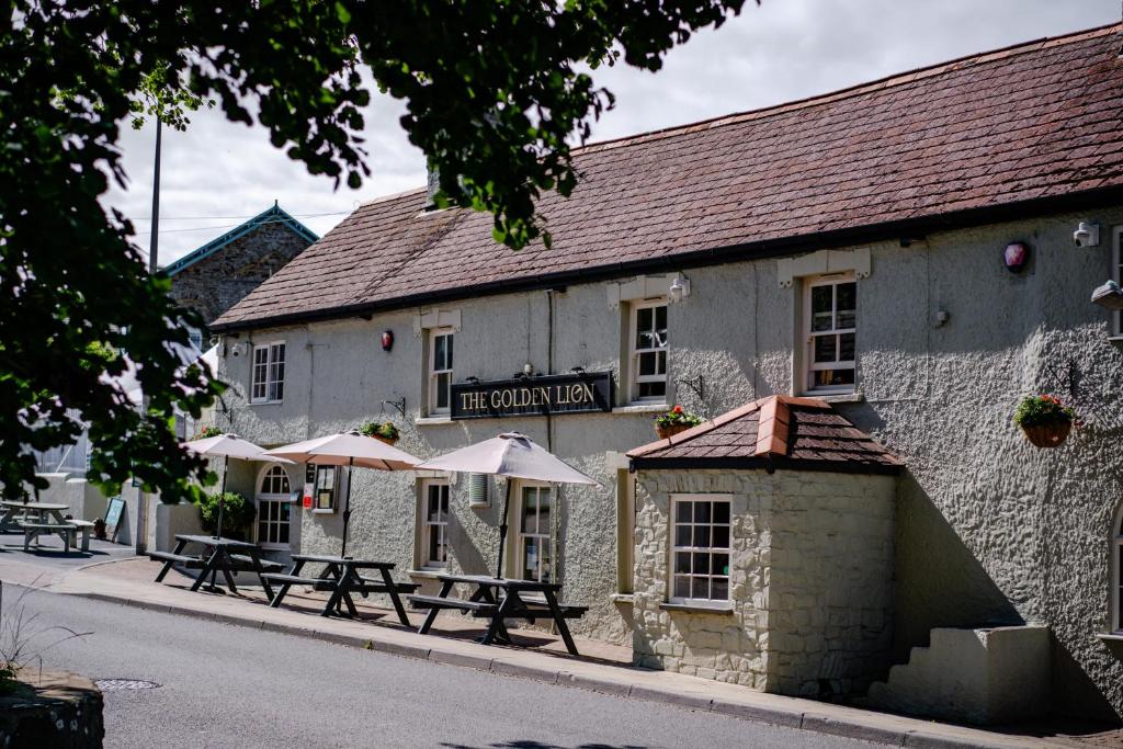 un edificio con mesas y sombrillas delante en The Golden Lion, Newport, PEMBROKESHIRE, en Newport