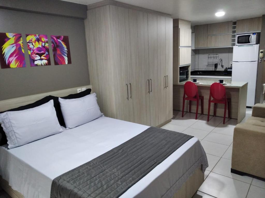 een slaapkamer met een bed en een keuken met rode stoelen bij Estudio Confort West Flat com ótima localização. in Mossoró