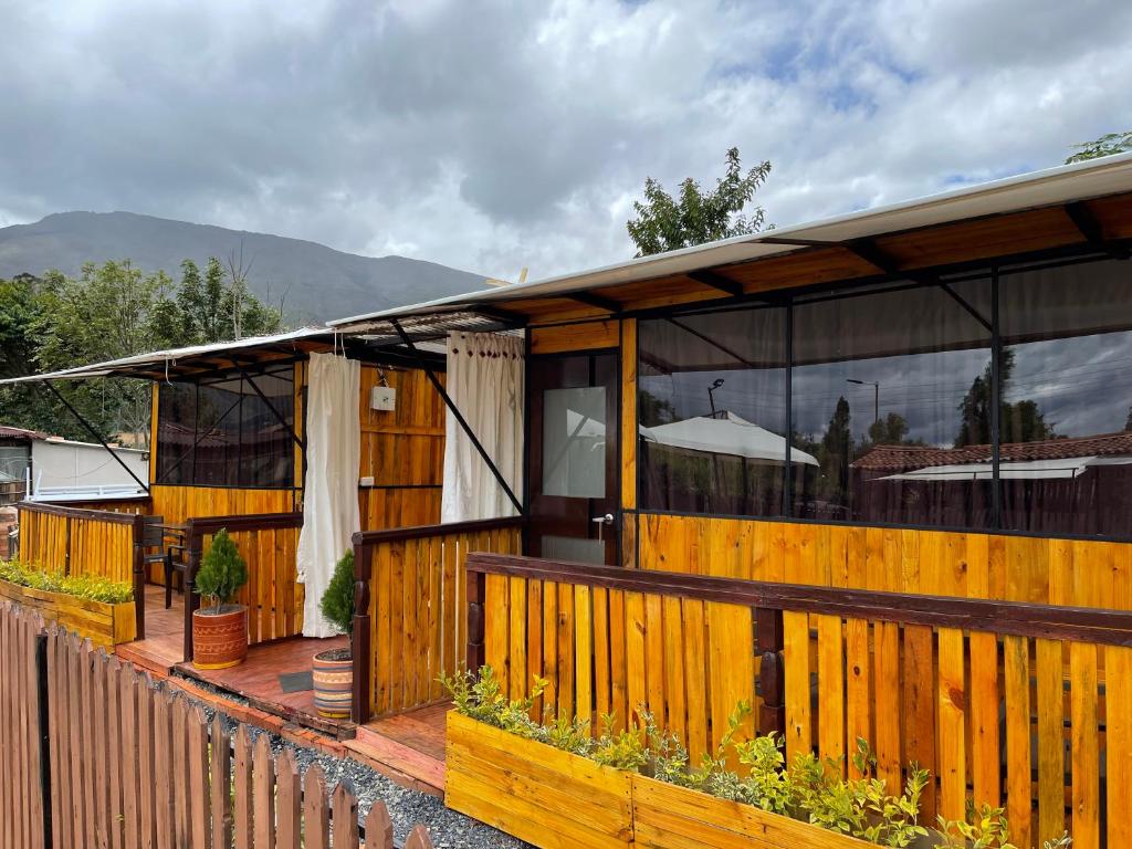 ein Haus mit einer Holzterrasse mit einem Zaun in der Unterkunft Glamping en villa in Villa de Leyva