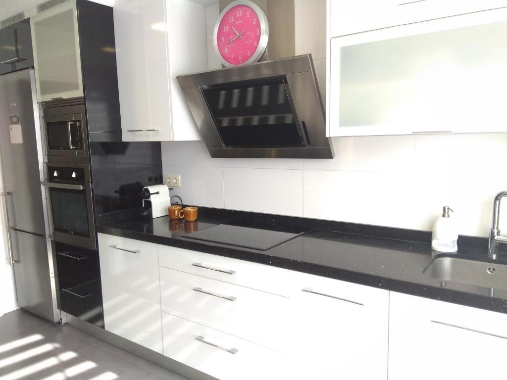 a kitchen with white cabinets and a clock on the wall at Aixula Lekeitio - Garaje opcional, reformado y céntrico in Lekeitio