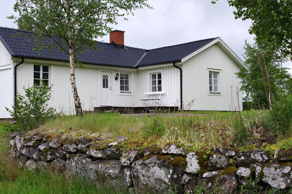 une maison blanche avec un mur en pierre devant elle dans l'établissement Göta kanal Hajstorp, à Töreboda