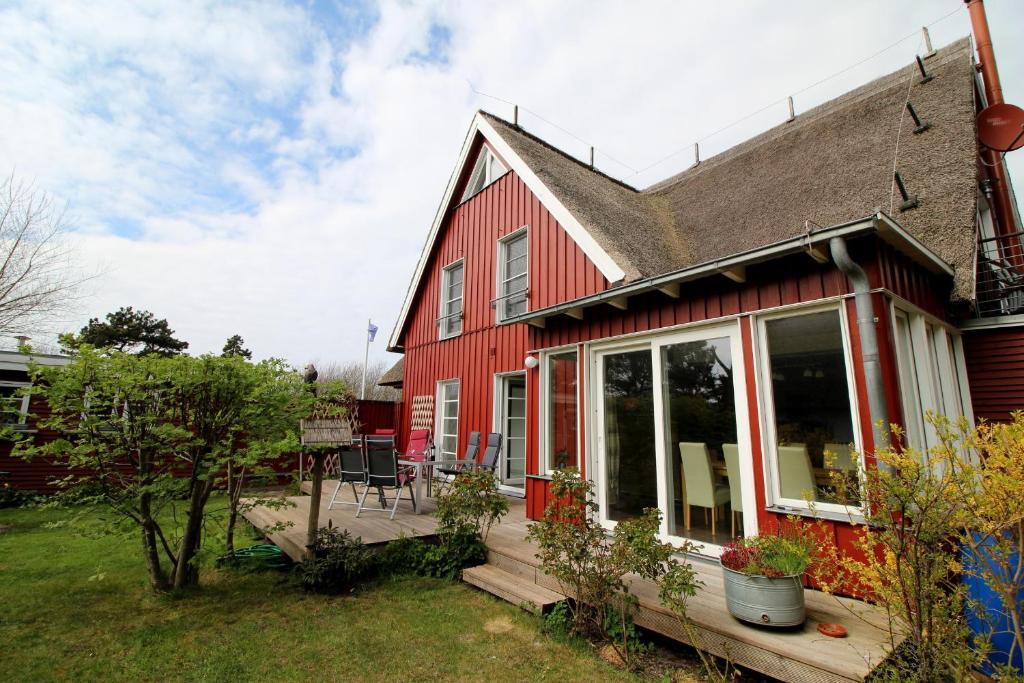 una casa roja con porche y patio en Nebelstation en Wustrow