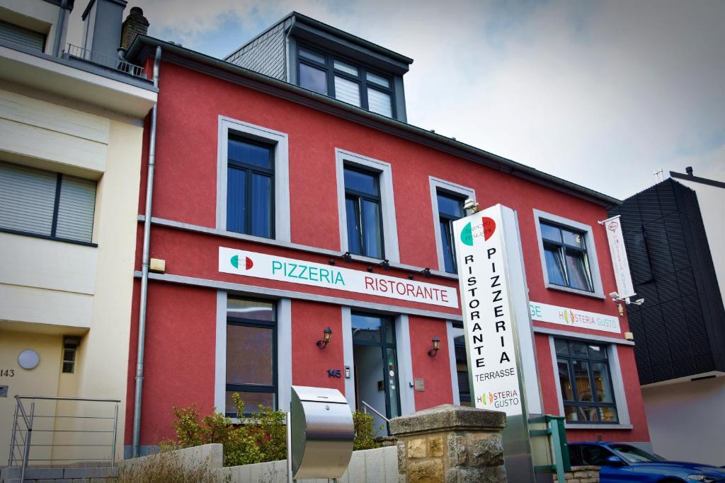 un edificio rojo con un cartel delante en Hosteria Gusto, en Esch-sur-Alzette