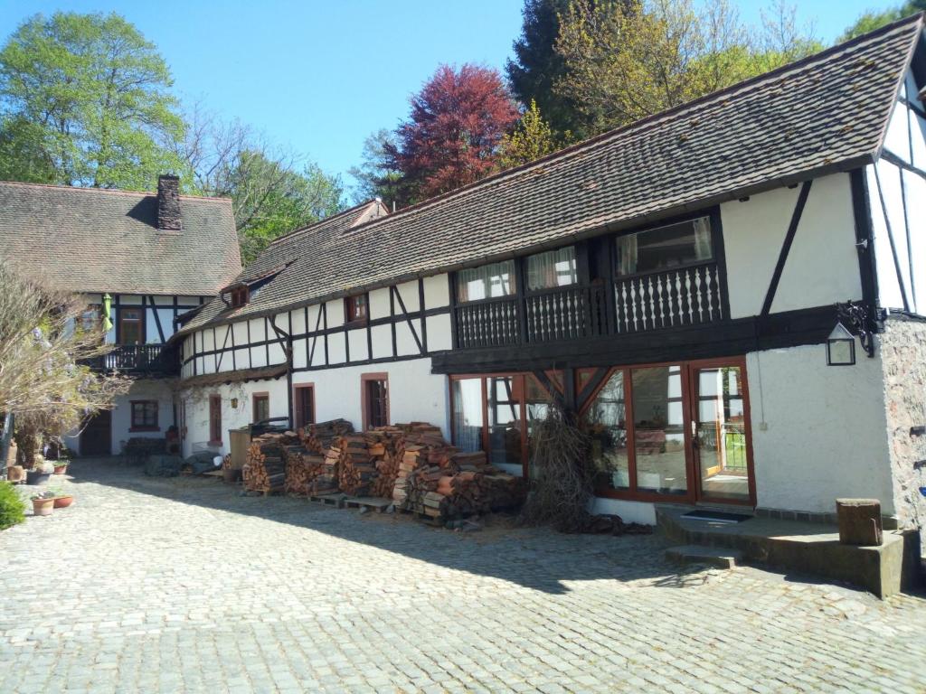 un edificio blanco y negro con un montón de troncos en Pulvermühle - 3 Zimmer Maisonette inkl Bad am Stettbach im NATURA 2000 Gebiet mit 12500 qm Garten, en Seeheim-Jugenheim