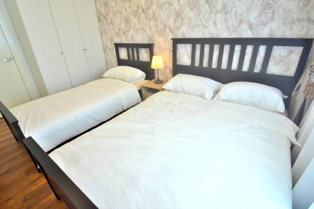 two twin beds in a bedroom with a lamp at Vivacity Jazz Suite New Luxury Cozy Home A13 in Kuching