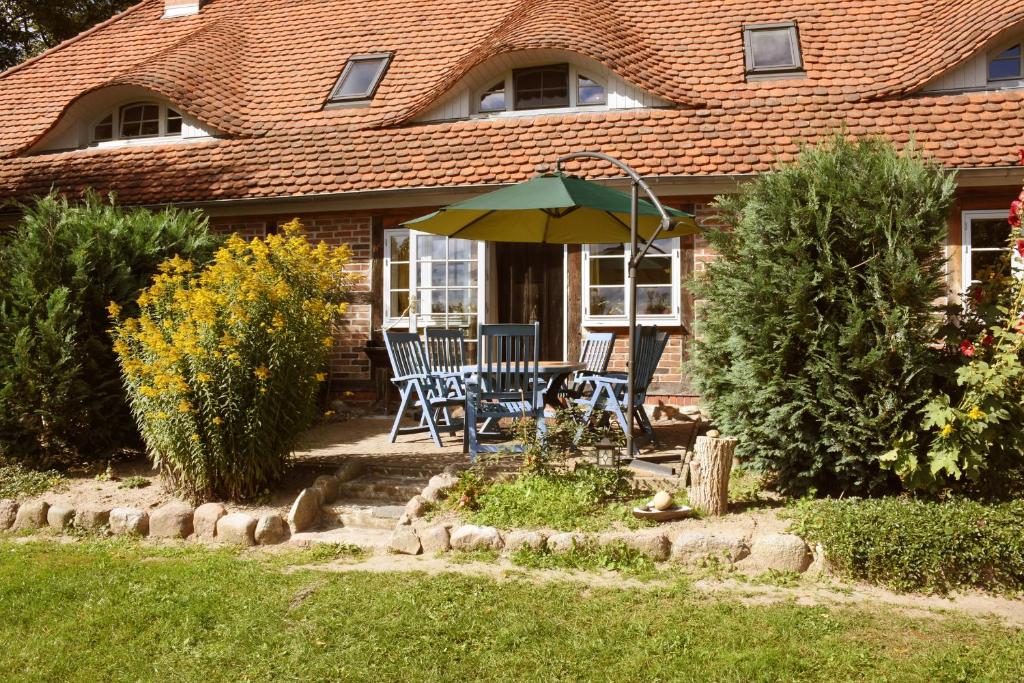 una casa con mesa, sillas y sombrilla en Landhaus im Grünen - Sine Tempore, en Grammendorf