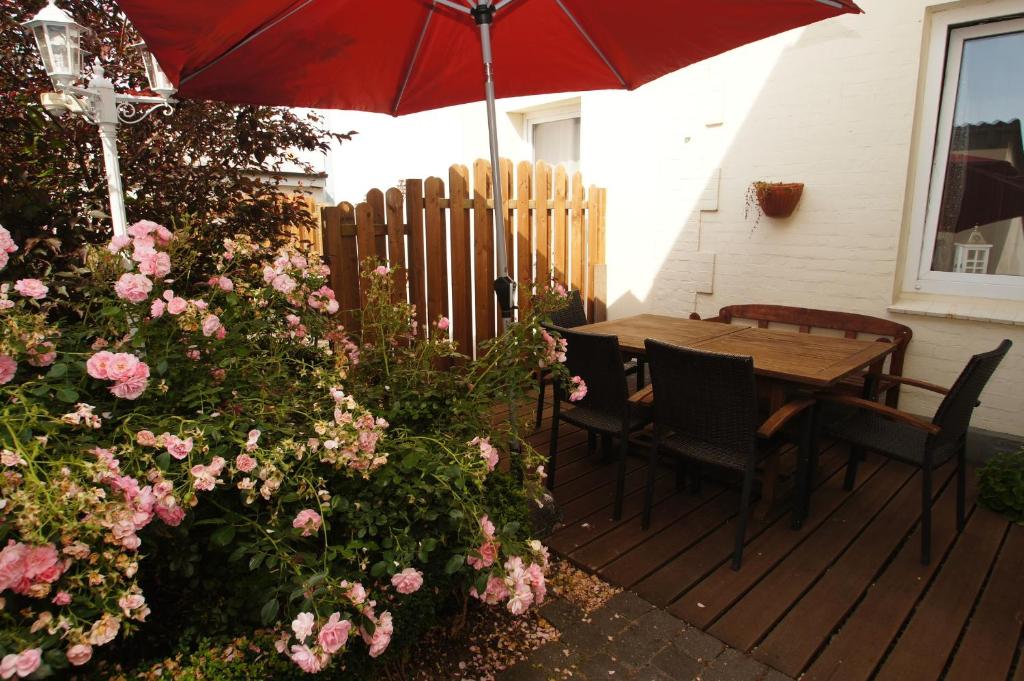a wooden deck with a wooden table with a red umbrella at Strandnelke in Dahme