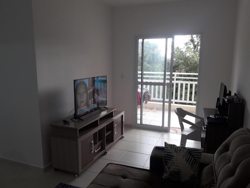 uma sala de estar com televisão e uma porta para uma varanda em APTO 02 DORM BERTIOGA em Bertioga