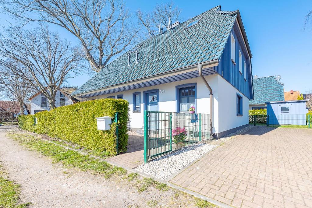 a white and blue house with a fence at Haus Bullerbü in Zingst