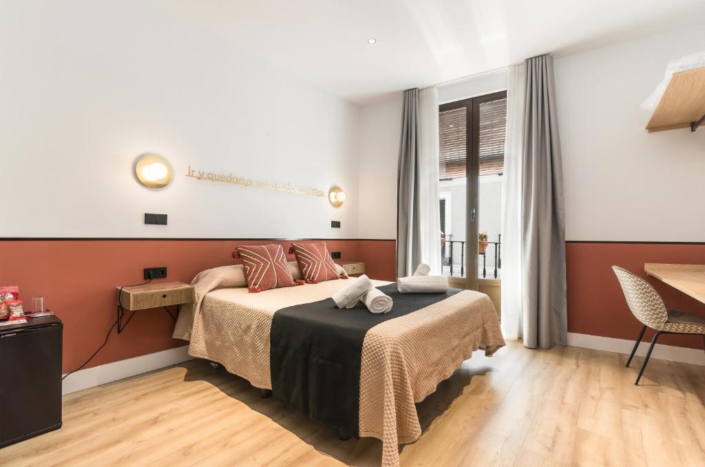 a bedroom with a bed and a table and a window at Cálamo Guesthouse in Madrid