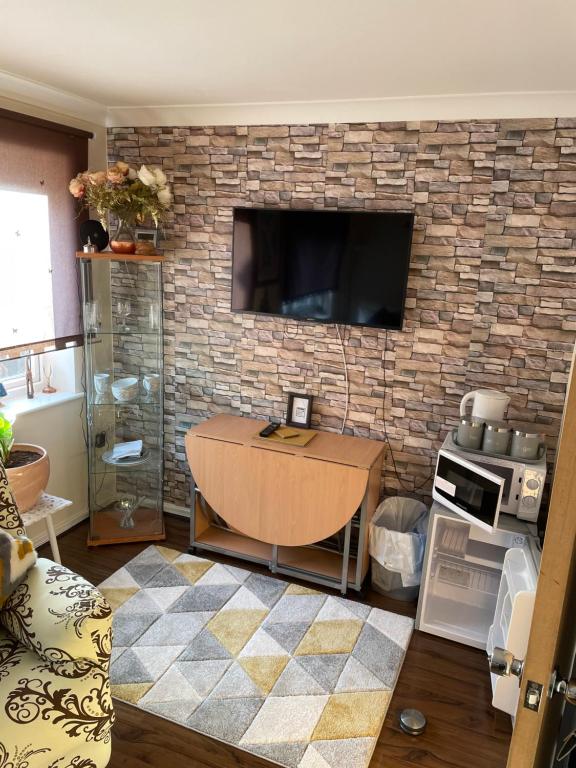 a living room with a table and a tv on a brick wall at TiSi Choice in Northfleet