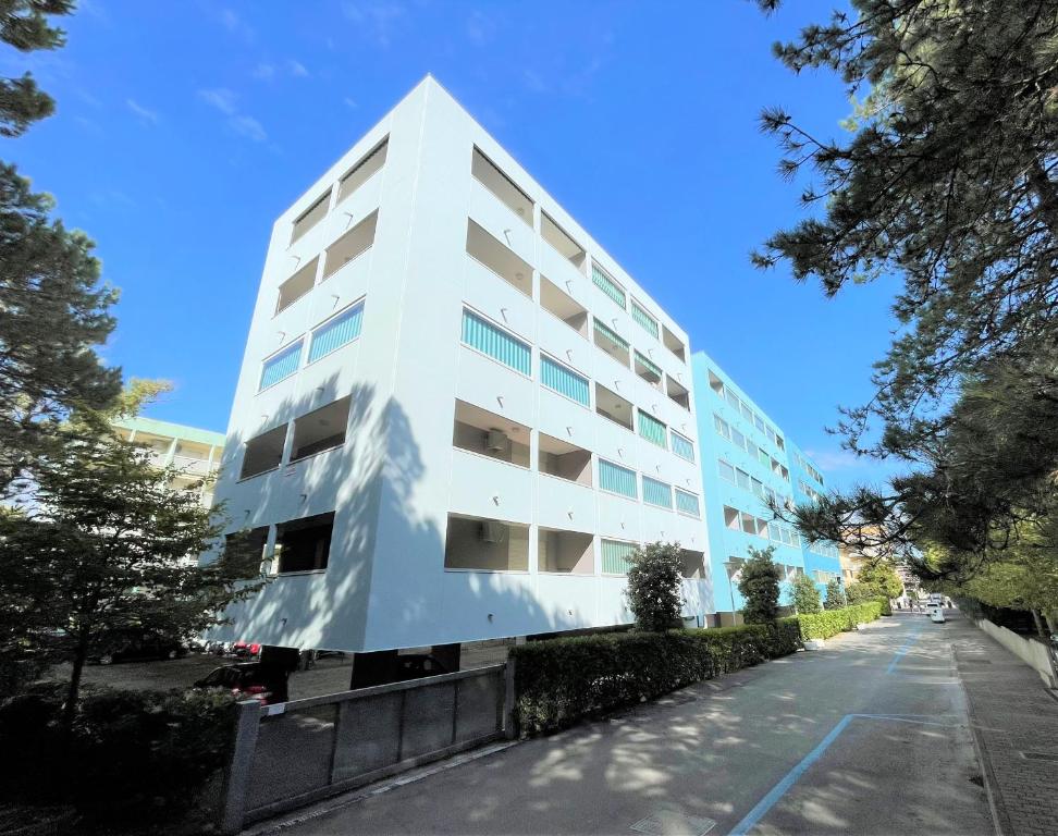 ビビオーネにあるIsola Clara - Appartamentiの通り側に木々が並ぶ高い白い建物