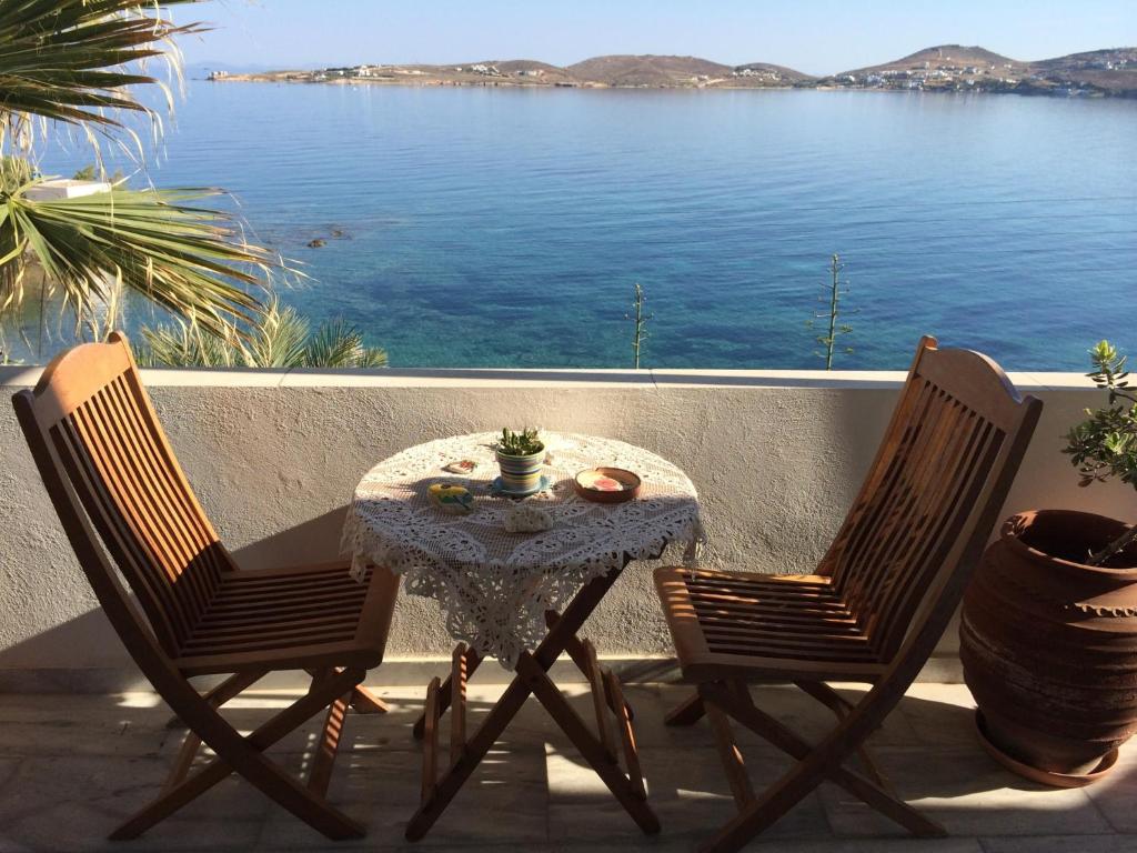 una mesa y 2 sillas en un patio con vistas al agua en Paros Rooms Dora, en Parikia