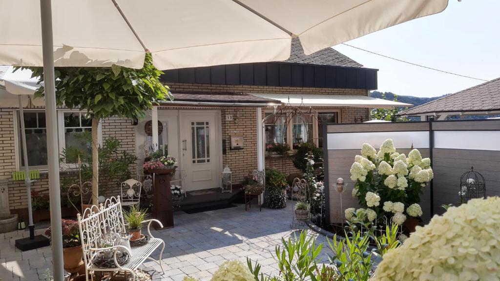 ein Haus mit einer Terrasse mit Stühlen und einem Sonnenschirm in der Unterkunft Landhaus Julia in Kobern-Gondorf