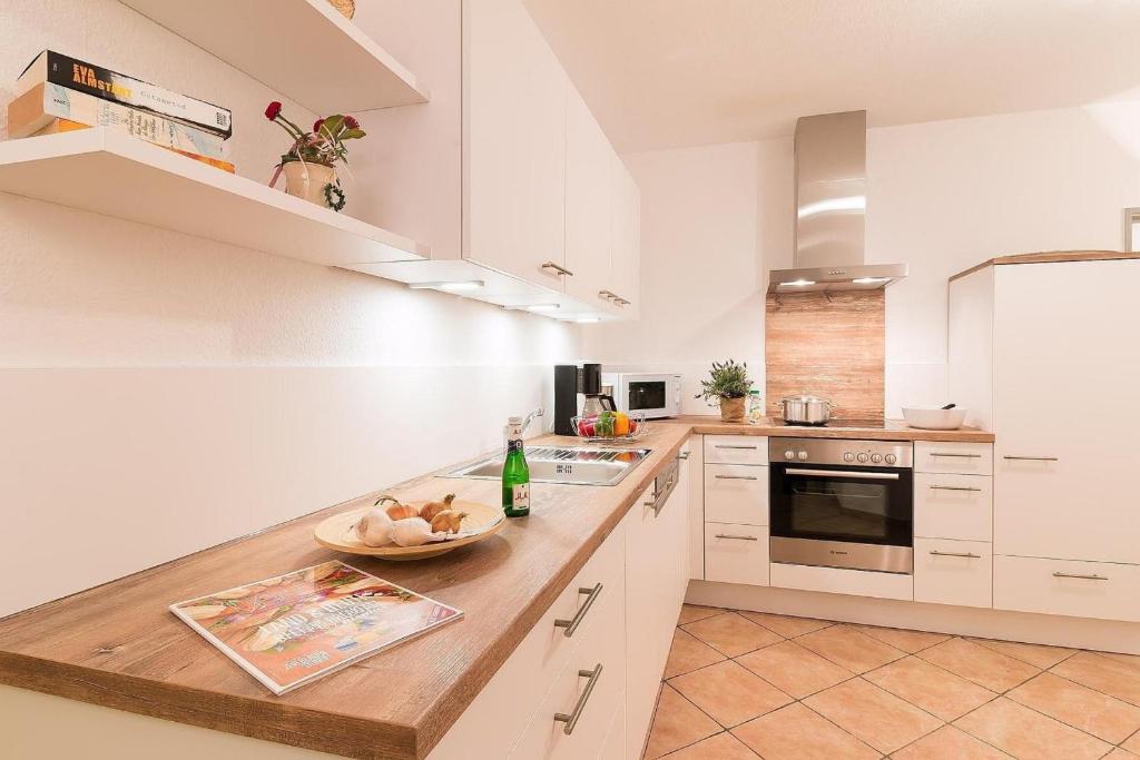 a kitchen with white cabinets and a bowl of food on a counter at W1 - Gästehaus Christian-Westphal-Str 60 - FERIENDOMIZIL HOLLICH in Grömitz