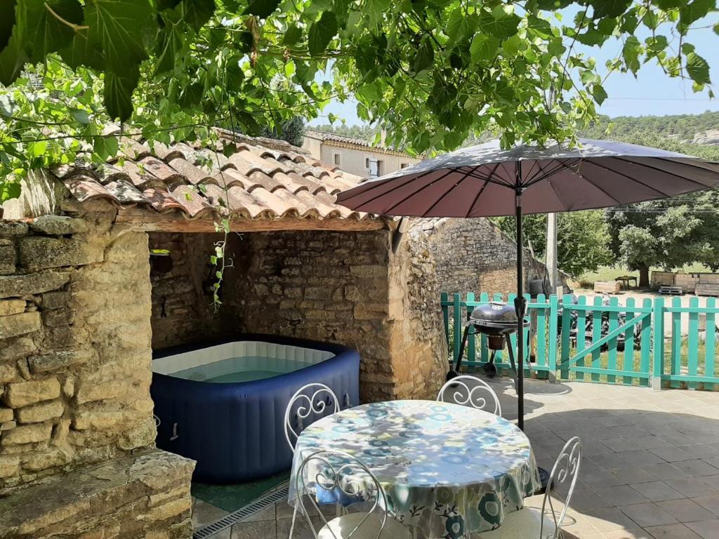 a table and an umbrella next to a bath tub at Gite au cœur du Luberon in Goult