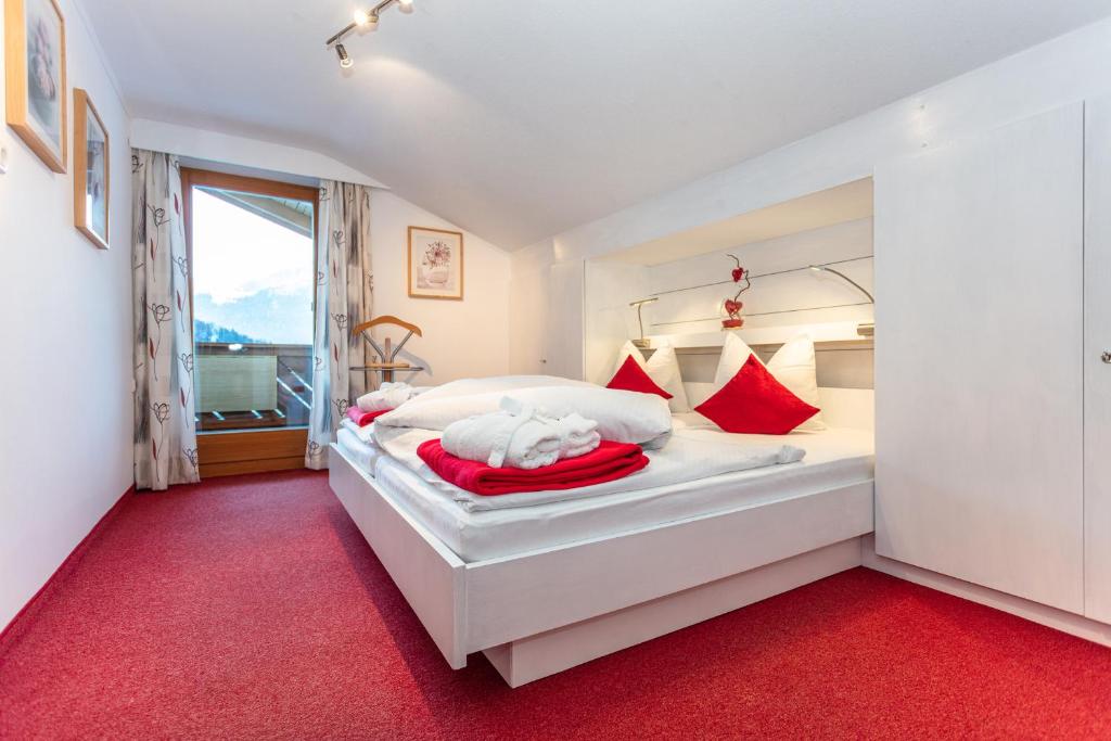 a bedroom with a large white bed with red accents at Komfortferienwohnung "Idylle" in Schwaigs
