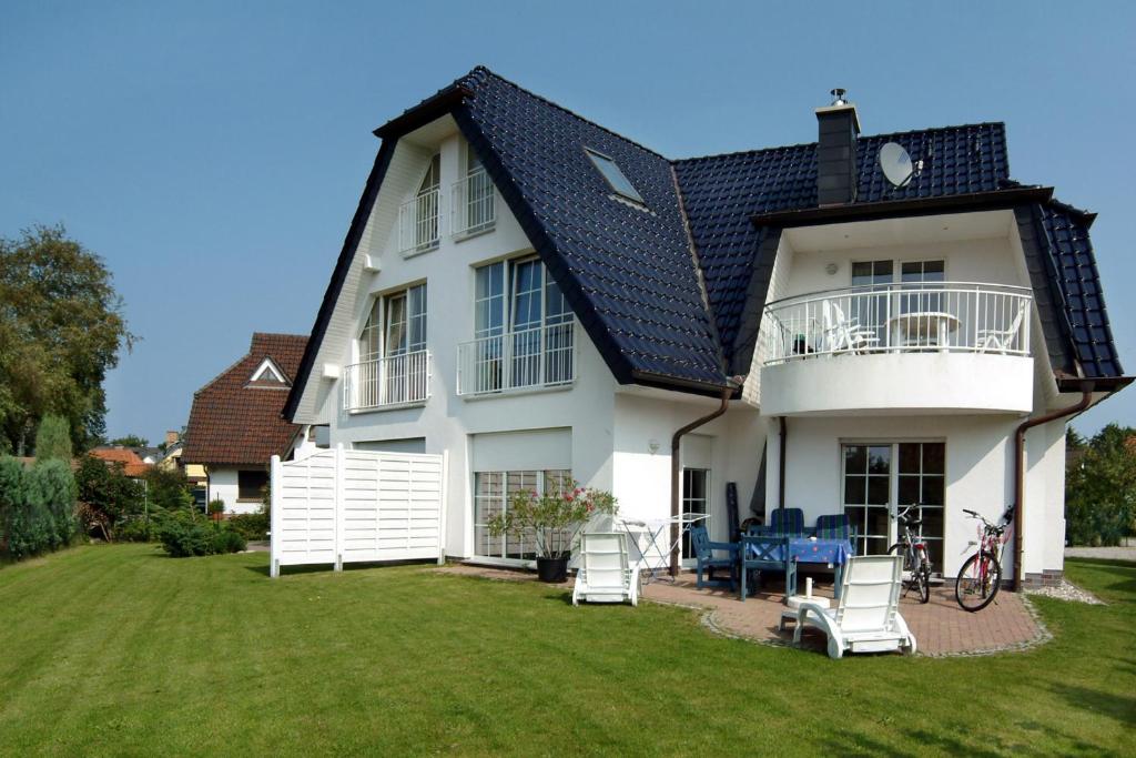 ein weißes Haus mit einem schwarzen Dach und einem Hof in der Unterkunft Nele, Whg 1 in Zingst