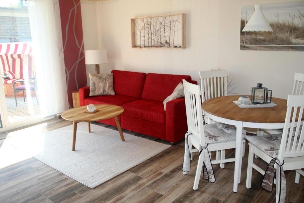 ein Wohnzimmer mit einem roten Sofa und einem Tisch in der Unterkunft Strandhafer V4W2 in Dierhagen