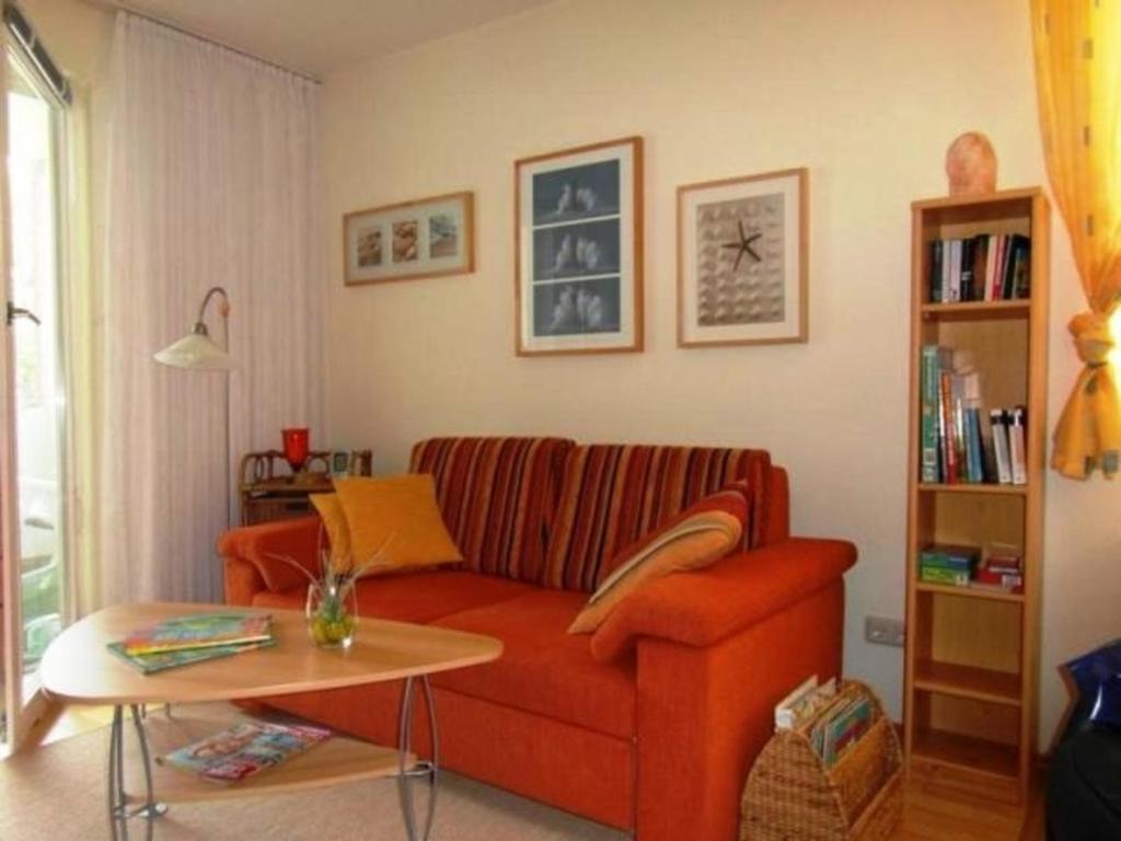 a living room with a red couch and a table at Fewo 91 WHG B 18 in Burhave in Burhave