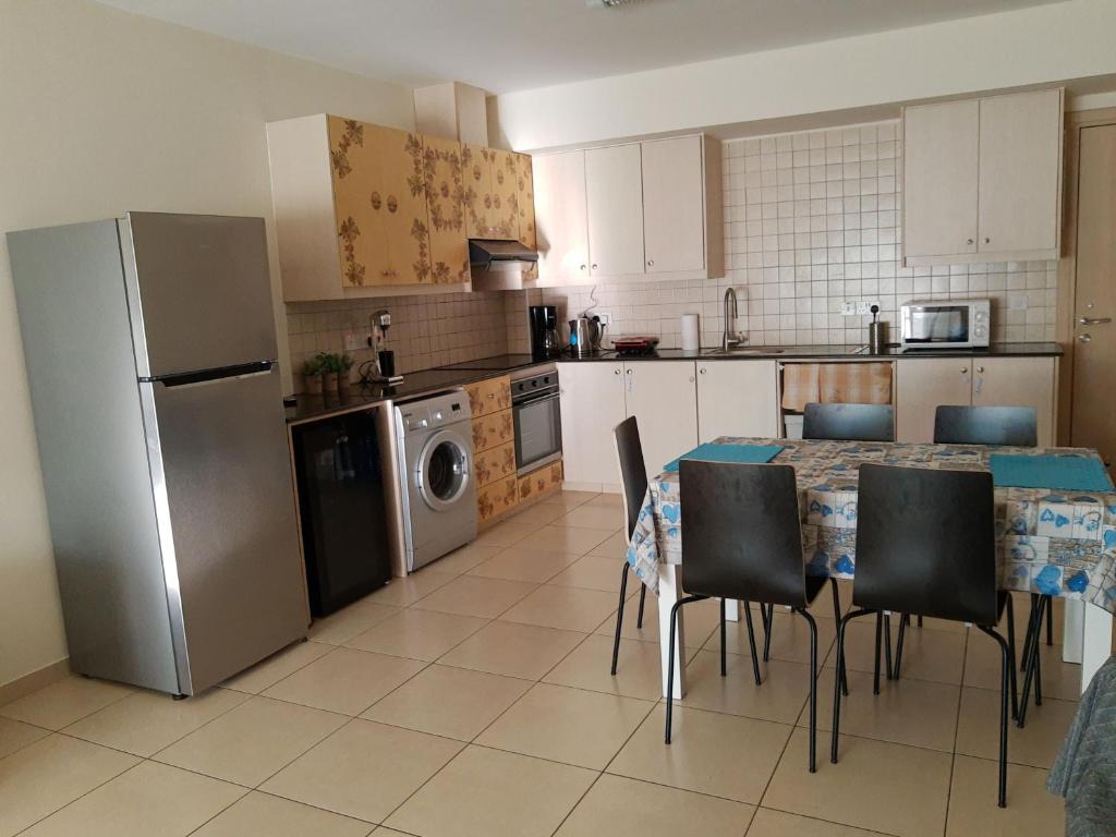 y cocina con mesa, sillas y nevera. en Larnaca Xylophagou 2-bedroom apartment with a shaded terrace en Xylophaghou