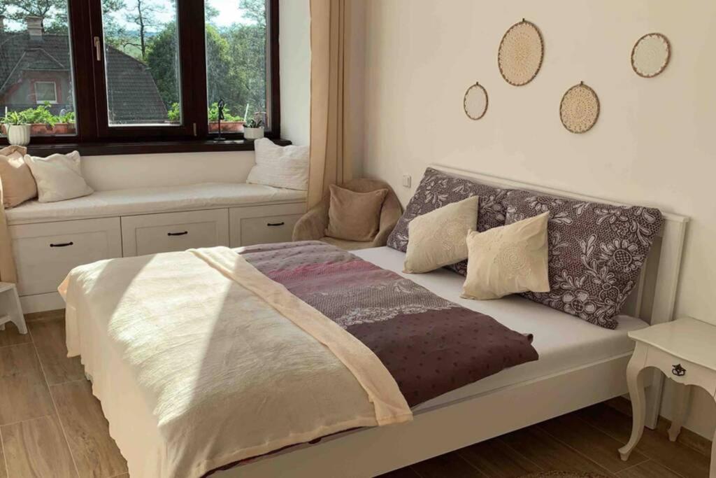 una camera da letto con un grande letto con cuscini e una finestra di Tři okna do hor-Celý byt k pronájmu a Rýmařov