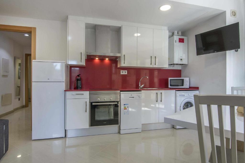 een keuken met witte apparatuur en een rode muur bij Kisa Apartments de Manresa in Manresa