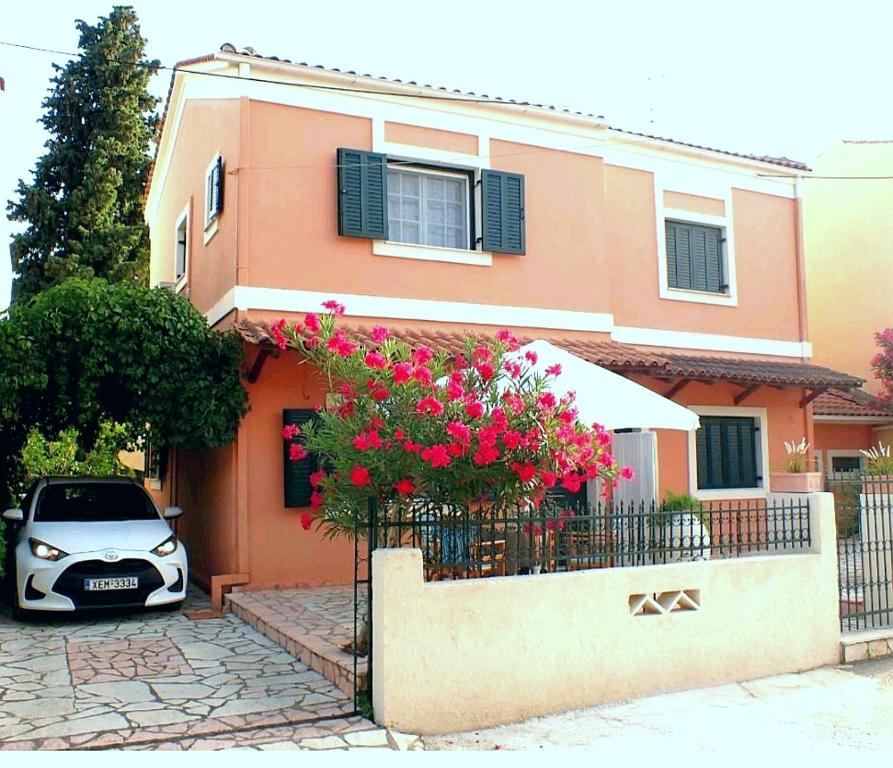een auto geparkeerd voor een huis met roze bloemen bij Μaisonette Deja Bleu in Sivota