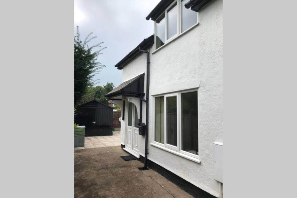 a white house with a window on the side of it at Charming just renovated 2 bed cottage in the centre of village in Hartford