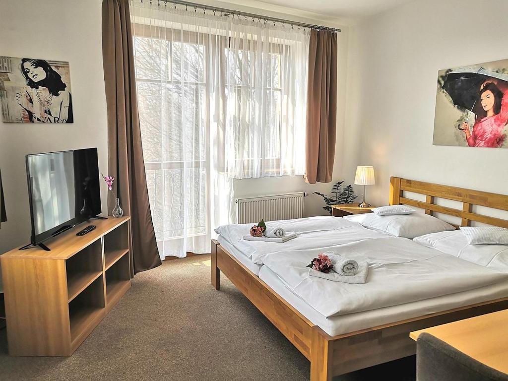 Hotel U Brány في بلدة أوهِرسكي بروت: غرفة نوم بسريرين وتلفزيون بشاشة مسطحة