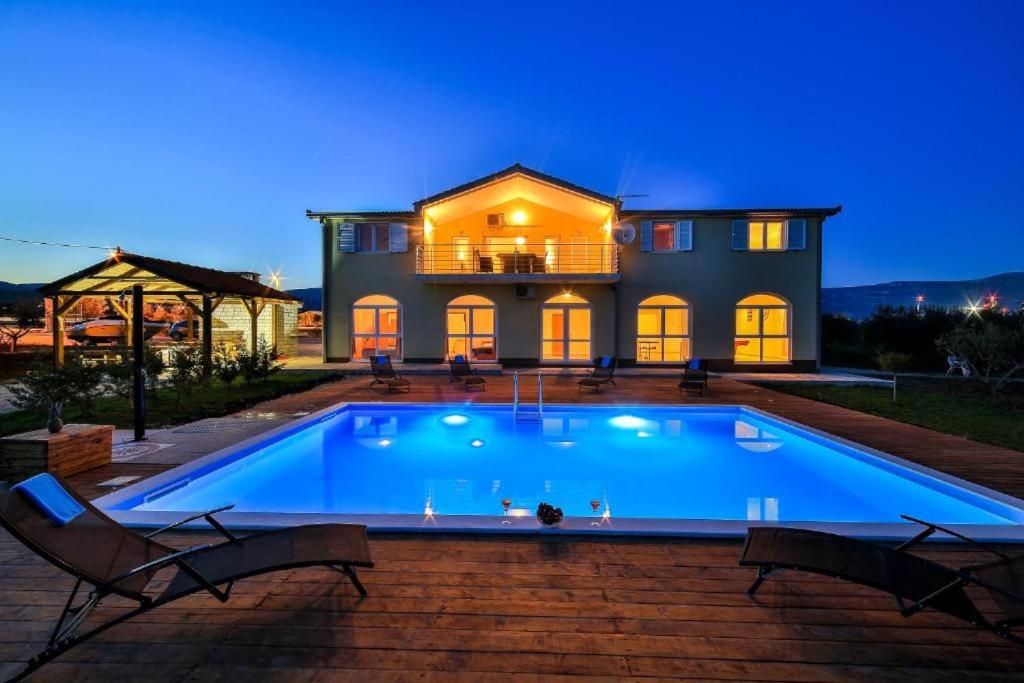 a house with a large swimming pool in front of it at Orange Tree Garden in Kastel Stafilic
