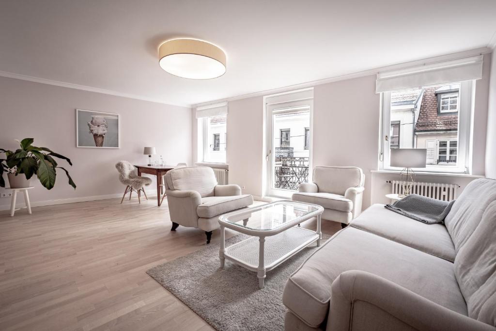 uma sala de estar com um sofá, cadeiras e uma mesa em Boutique Charme Apartments em Baden-Baden