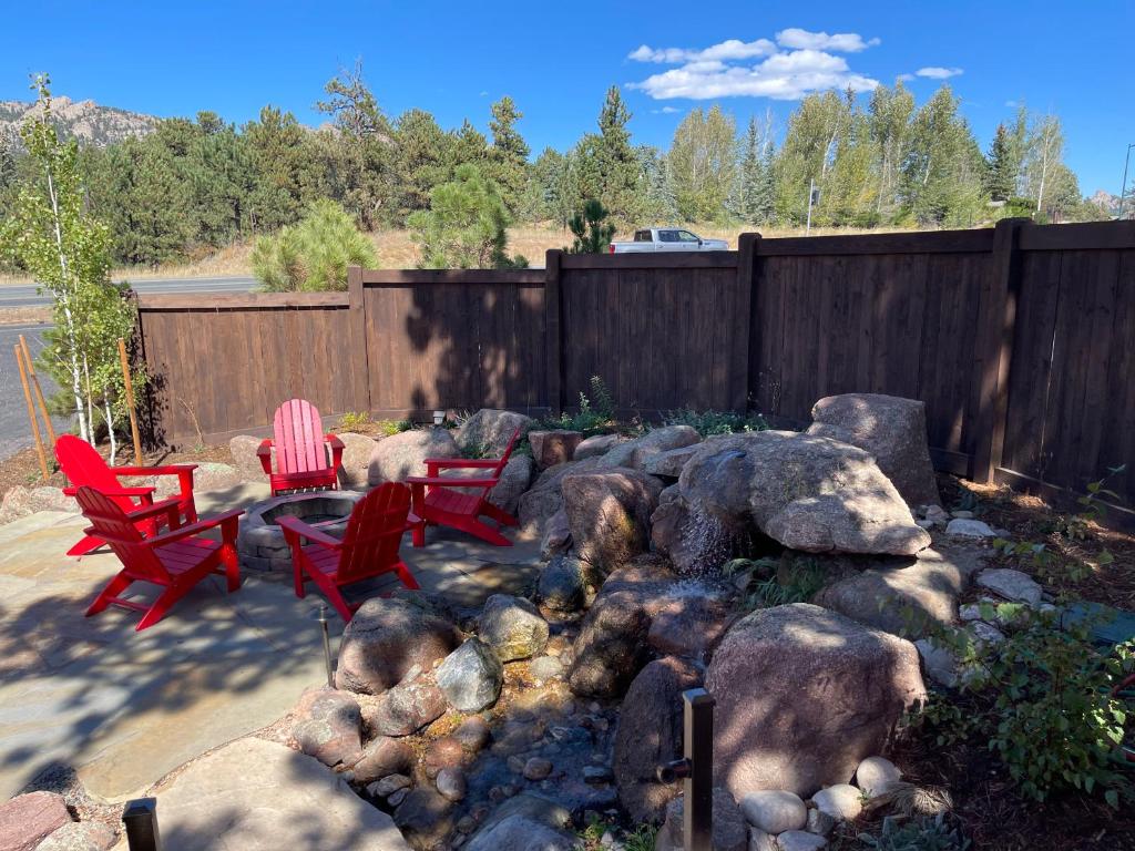 une cour avec des chaises rouges, des rochers et une clôture dans l'établissement Estes Mountain Inn, à Estes Park